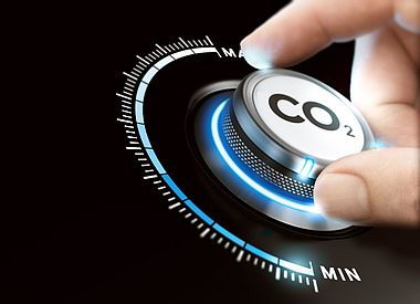Man dreht einen Kohlendioxidknopf, um die Emissionen zu reduzieren. Konzept der CO2-Reduktion oder -Entfernung.